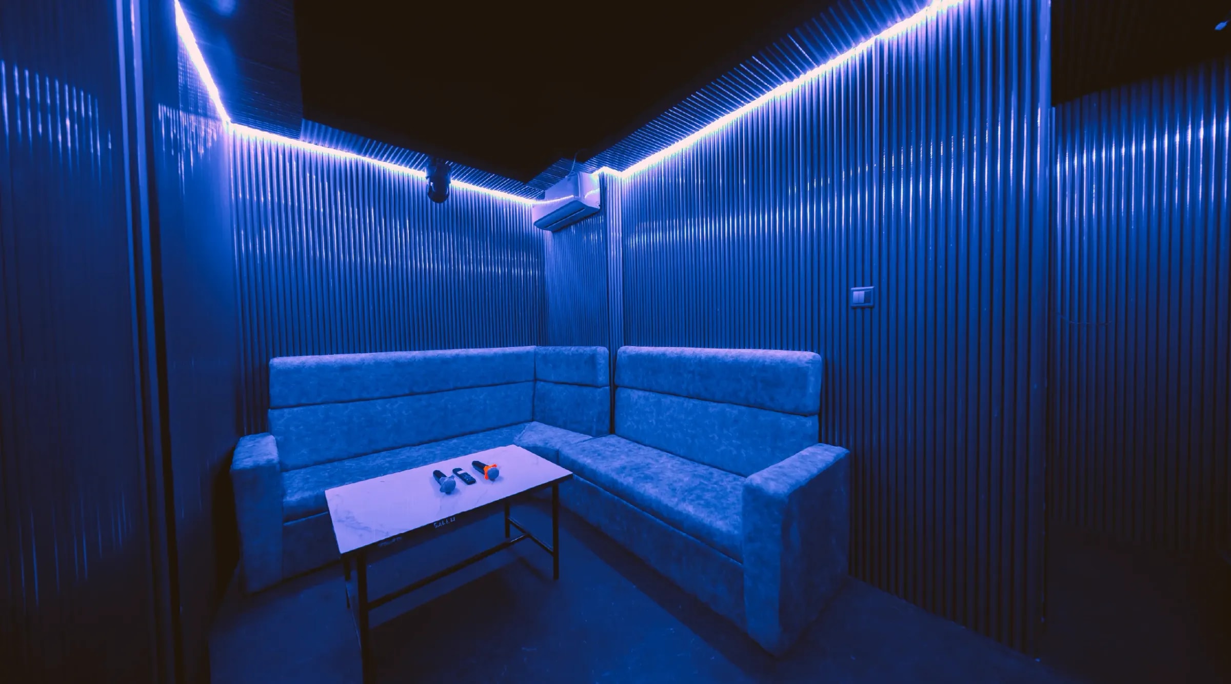 The Blue Room glowing with blue neon over a corner sofa